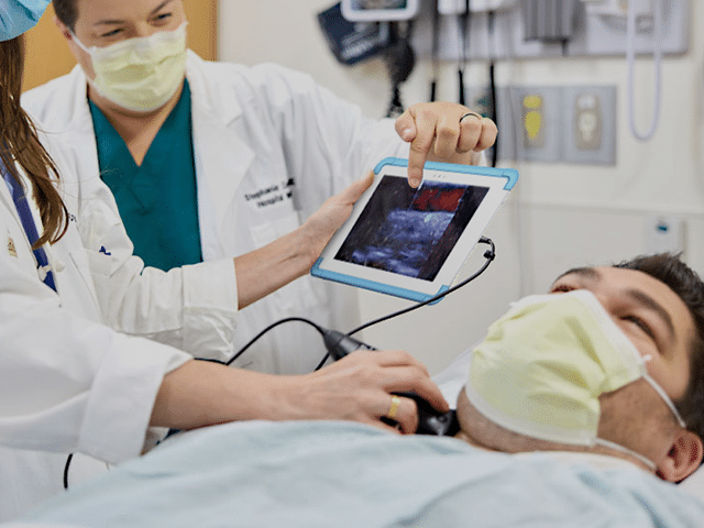 Doctors using a tablet to look at live imaging of a patients neck