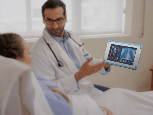 Doctor using a tablet to show medical images to a patient in bed